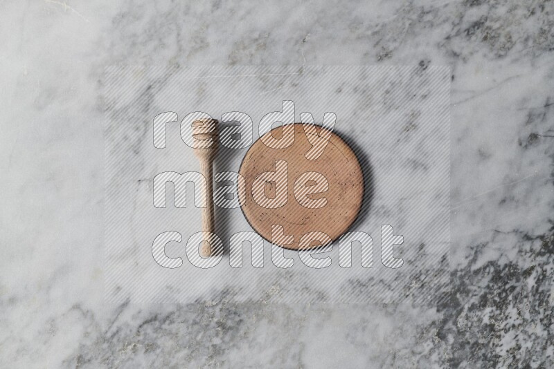 Beige pottery plate with wooden honey dipper on the side on grey marble background