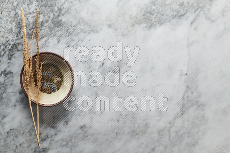 Wheat stalks on decorative pottery plate on grey marble background