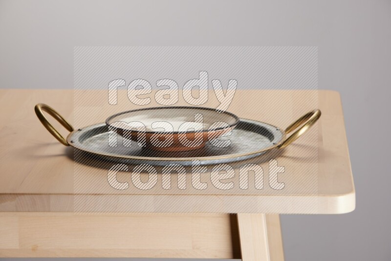 multicolored plate placed on a rounded stainless steel tray with golden handels on the edge of wooden table