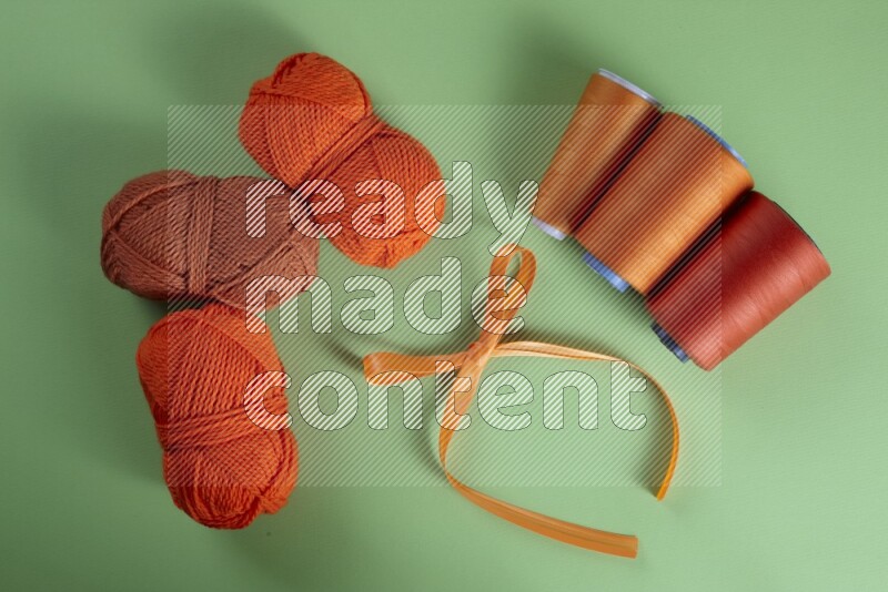 An orange collection of sewing and tailoring tools arranged on a green background