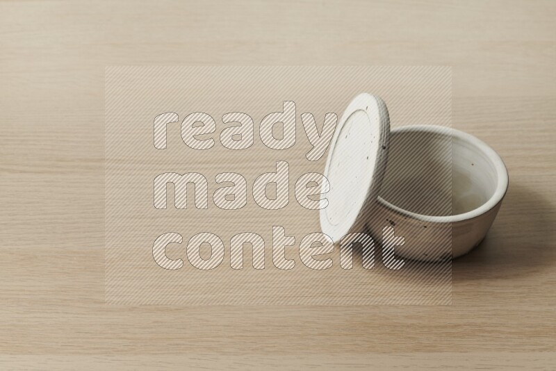 A white pottery bowl on light wooden background