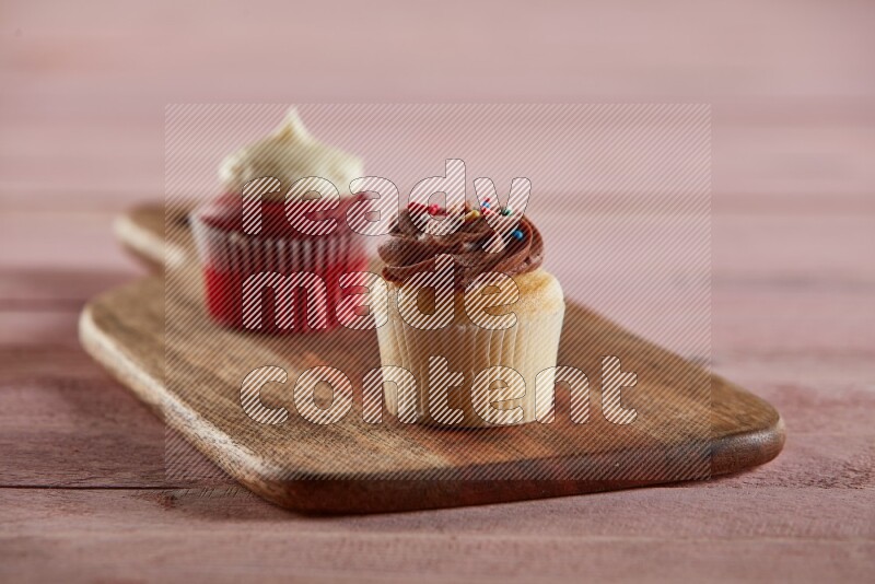 Vanilla mini cupcake topped with chocolate cream on a wooden board
