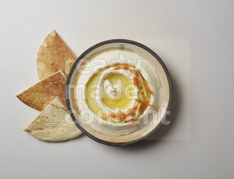 Lebnah garnished with sliced carrots &cucumber in a pottery plate on a white background