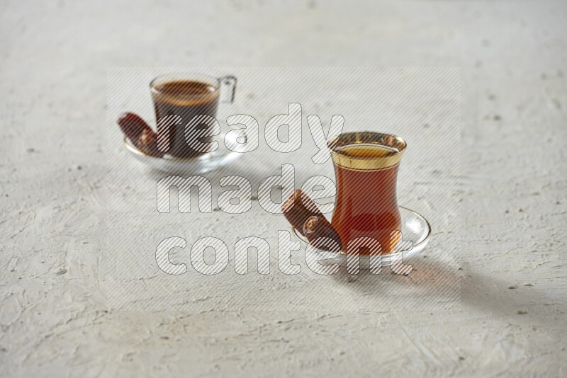 A tea glass cup with dates and coffee on textured white background