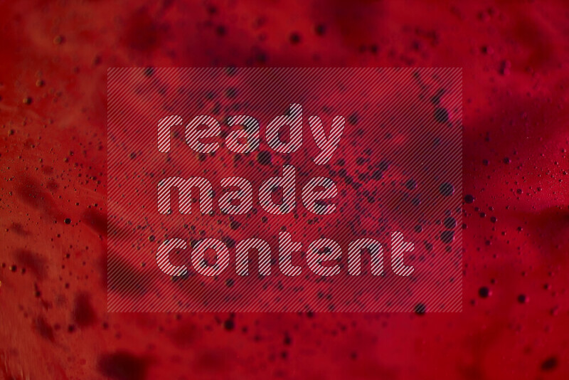 لقطات مقربة لقطرات ألوان مائية زرقاء على سطح الزيت على خلفية حمراء