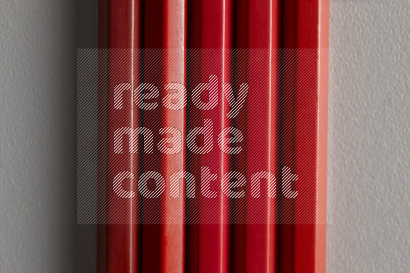 A collection of sharpened colored pencils arranged showcasing a gradient of red hues on grey background