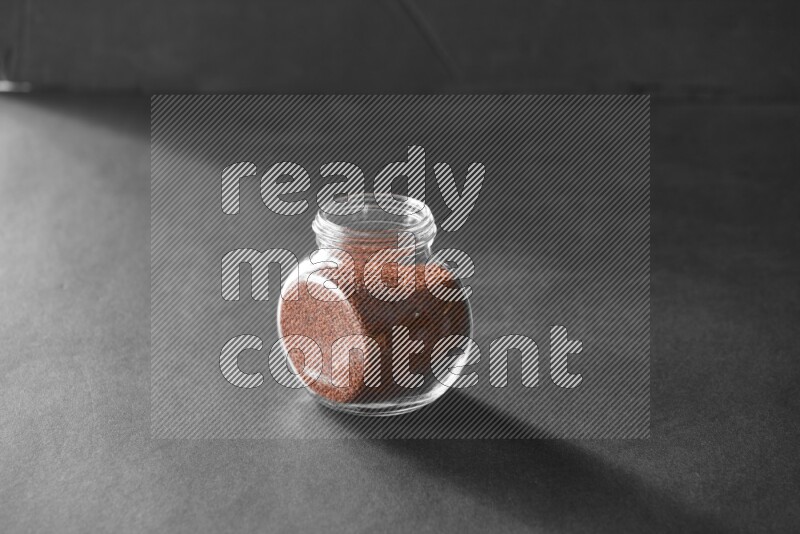 A glass spice jar full of garden cress on black flooring