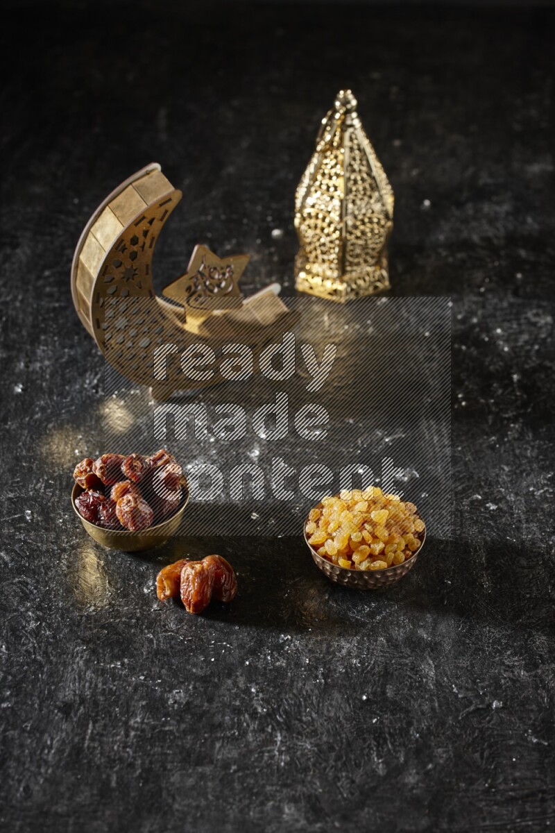 Dates in a metal bowl with raisins beside golden lanterns in a dark setup