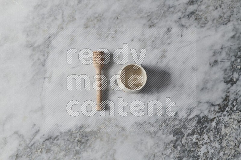 Beige pottery bowl with wooden honey dipper on the side on grey marble background