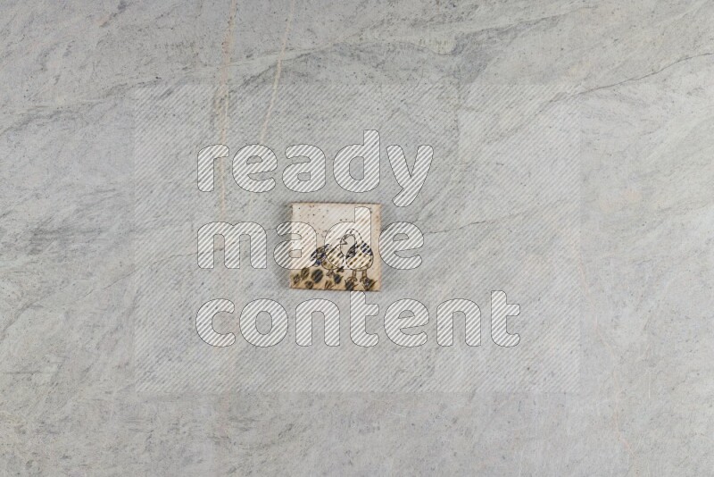 A decorative pottery coaster on grey marble background
