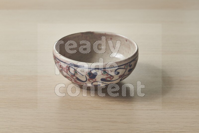 A decorative pottery bowl on light wooden background
