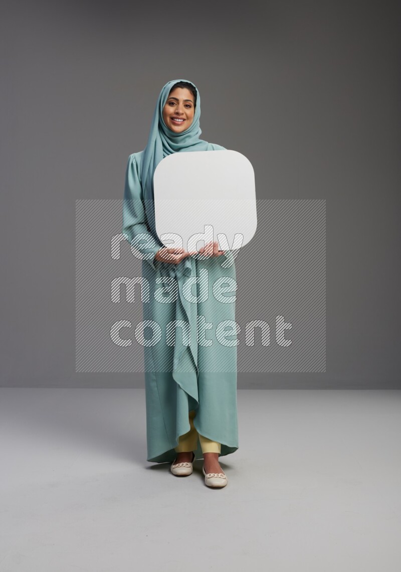 Saudi Woman wearing Abaya standing holding social media sign on Gray background