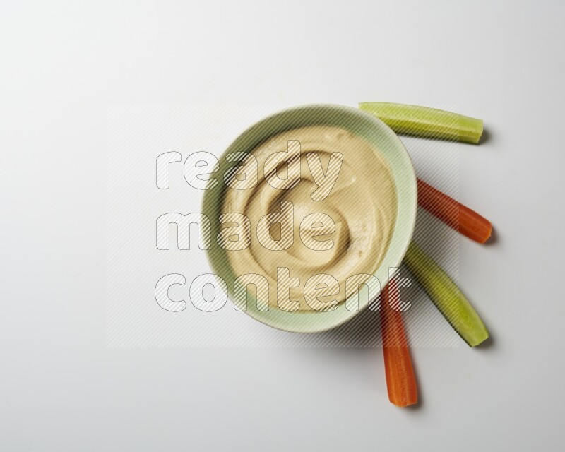 plain Hummus in a green plate on a white background