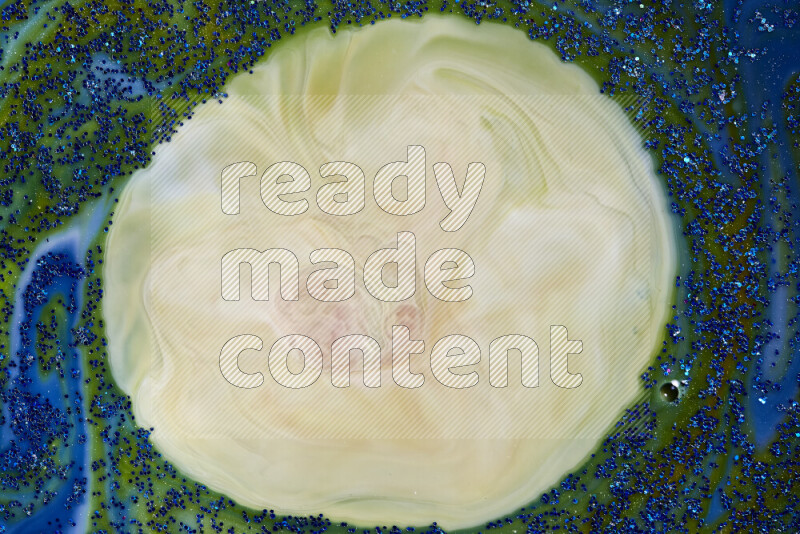 A close-up of sparkling blue glitter scattered on swirling blue and green background