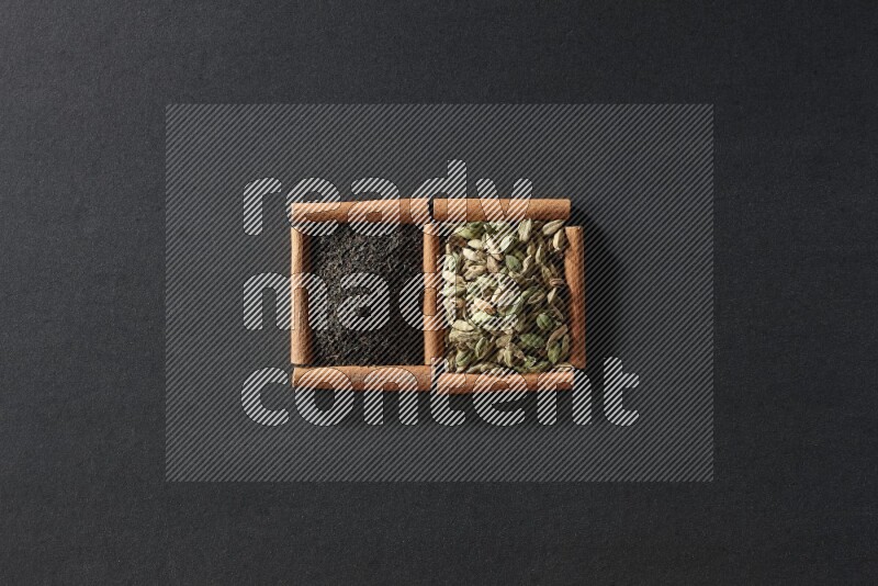 2 squares of cinnamon sticks full of cardamom and black tea on black flooring