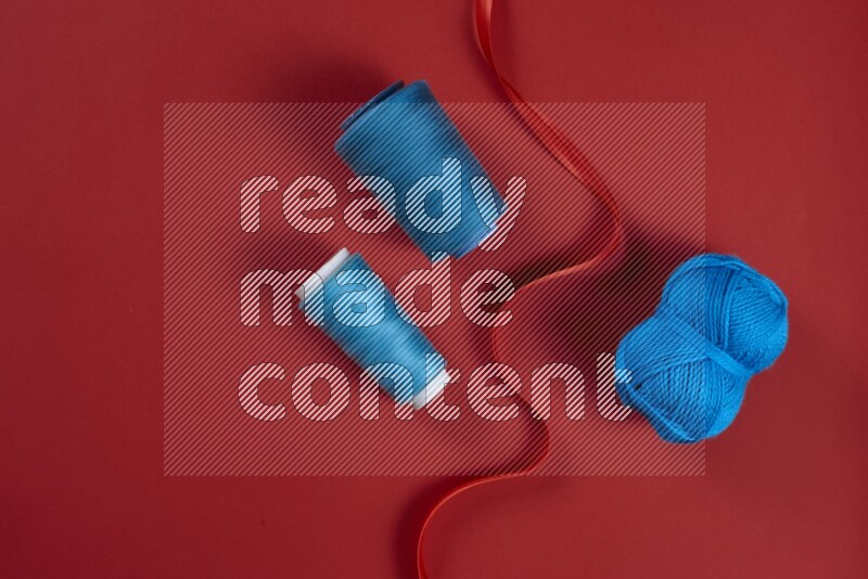 A blue and red collection of sewing and tailoring tools arranged on a red background
