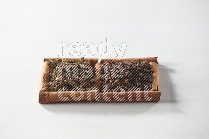 2 squares of cinnamon sticks full of cloves and dried basil on white flooring