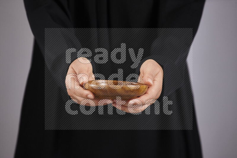 A woman in black abaya holding different wooden essentials in different positions