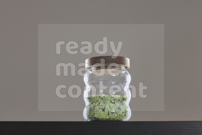 Sequins in a glass jar on black background