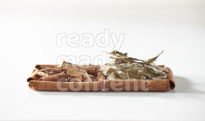 2 squares of cinnamon sticks full of cinnamon and bay laurel leaves on white flooring