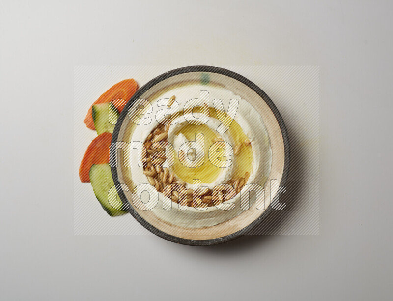 Lebnah garnished with pine nuts in a pottery plate on a white background
