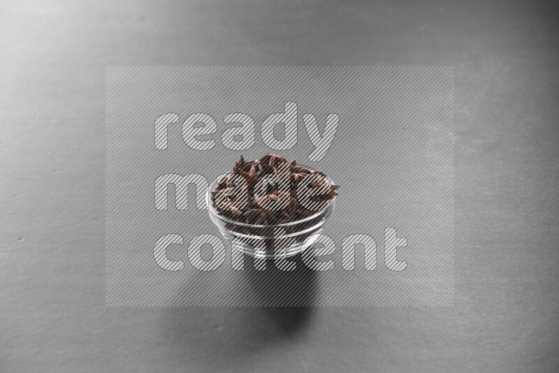 A glass bowl full of star anise on black flooring