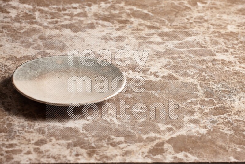 A multicolored pottery plate on beige marble background