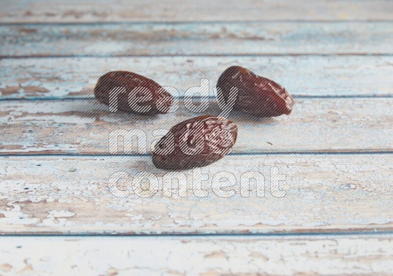 three madjoul dates on a light blue wooden background