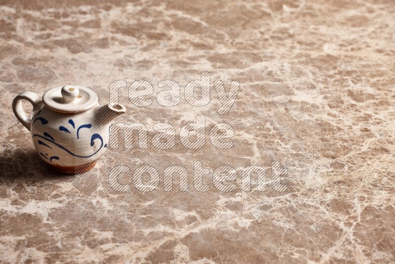 A pottery teapot on beige marble background