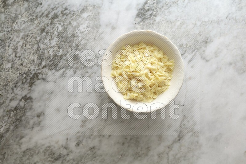 White bowl full of pasta on grey marble background
