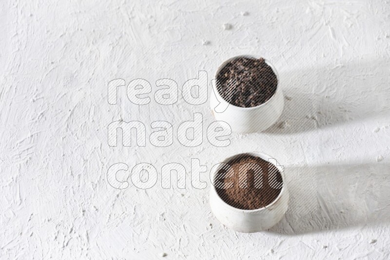 وعاءين من السيراميك بيج اللون، أحدهما مملوء بالقرنفل والآخر مملوء بالبودرة على أرضية بيضاء