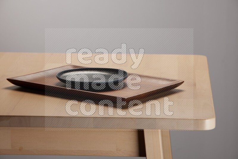 black plate on a rectangular wooden tray on the edge of wooden table
