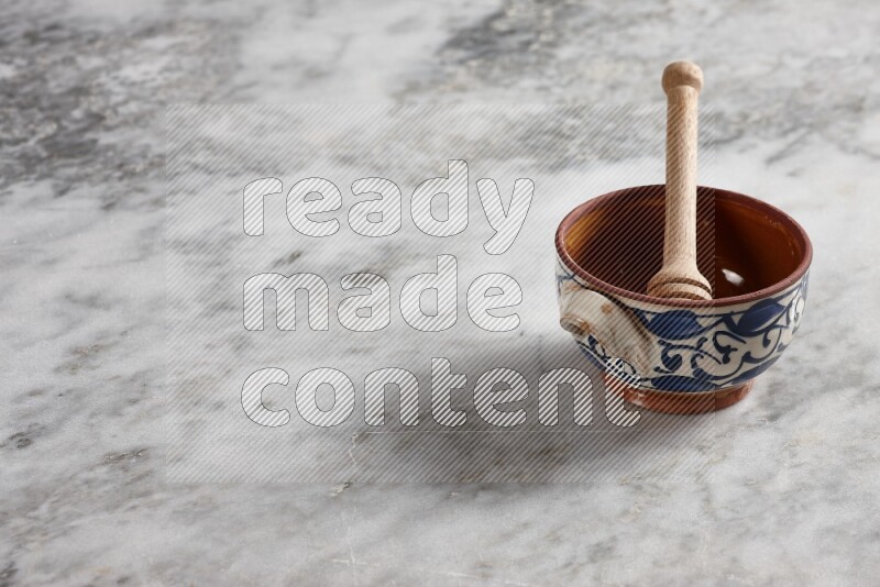 Decorative pottery pot with wooden honey dipper in it on grey marble background