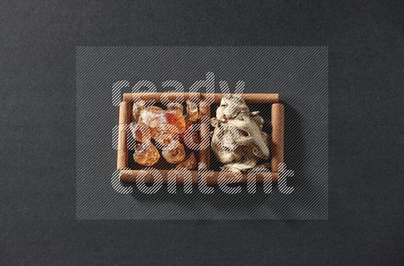 مربعان من أعواد القرفة ممتلئان بالزنجبيل المجفف والصمغ العربي علي خلفية سوداء