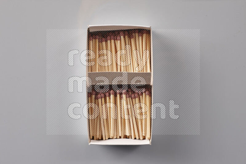 An open matchbox revealing wooden matches on a grey background