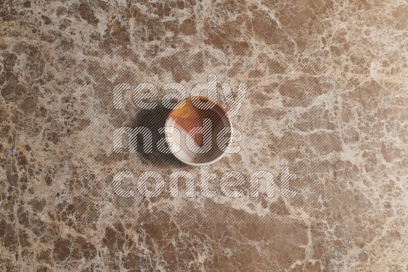 A multicolored pottery bowl on beige marble background