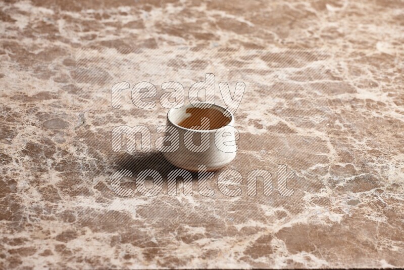 A beige pottery bowl on beige marble background