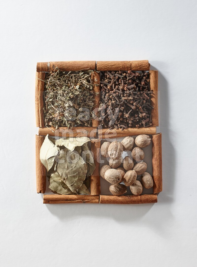 4 squares of cinnamon sticks full of bay laurel leaves, dried basil, cloves and nutmegs on white flooring