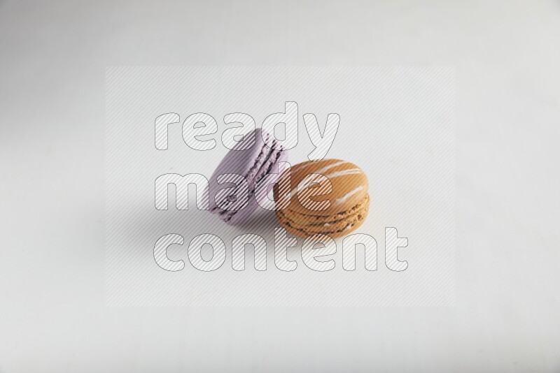 45º Shot of of two assorted Brown Irish Cream, and Purple Blueberry macarons on white background