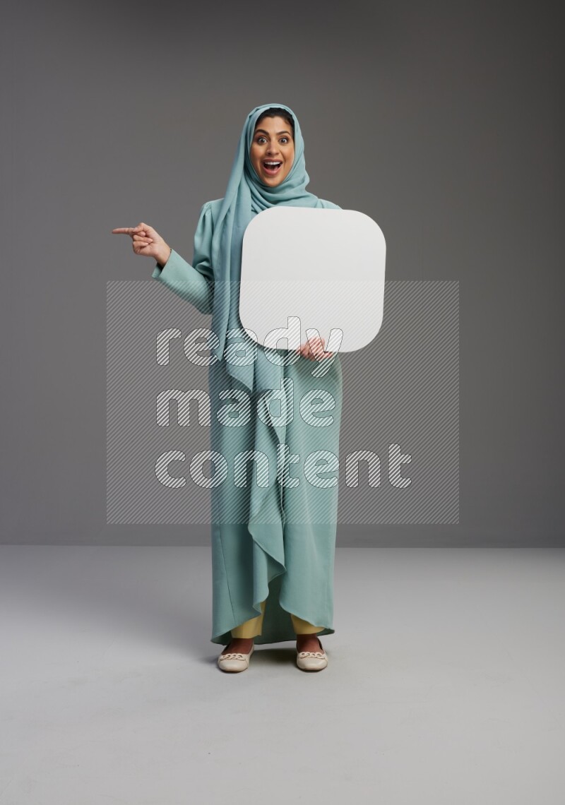 Saudi Woman wearing Abaya standing holding social media sign on Gray background