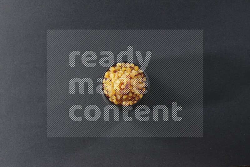 A black pottery bowl full of raisins on a black background in different angles
