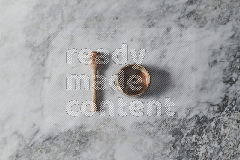 Brown pottery bowl with wooden honey dipper on the side on grey marble background