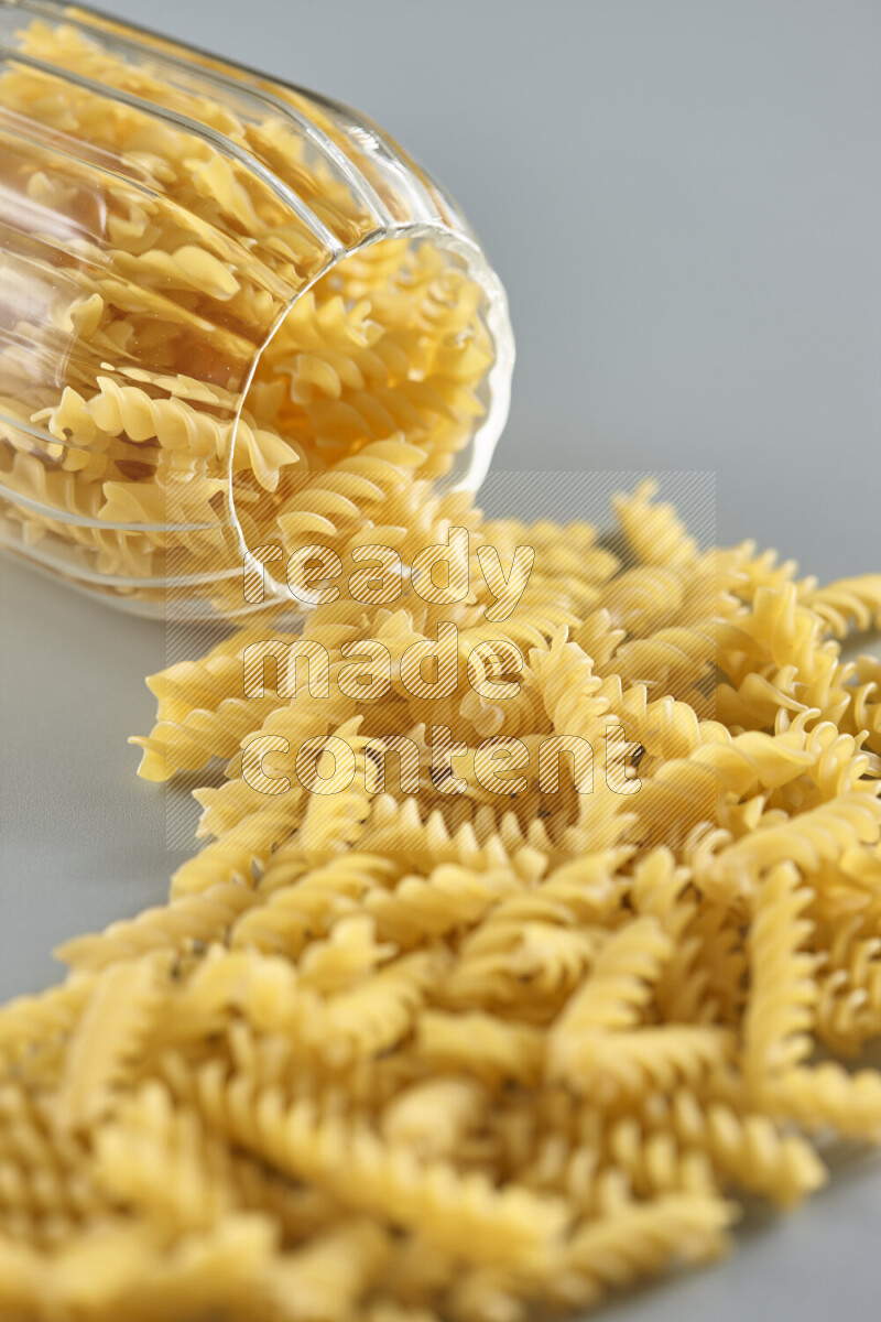 Flipped jar full of raw pasta on light blue background