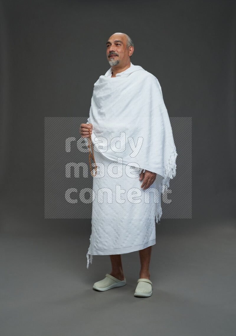 A man wearing Ehram Standing holding rosary on gray background