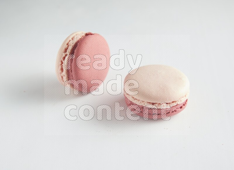 45º Shot of two Pink Litchi Raspberry macarons on white background