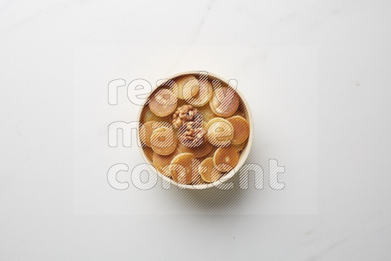 Top-view shot of walnut cereal pancakes in a round bowl on white background