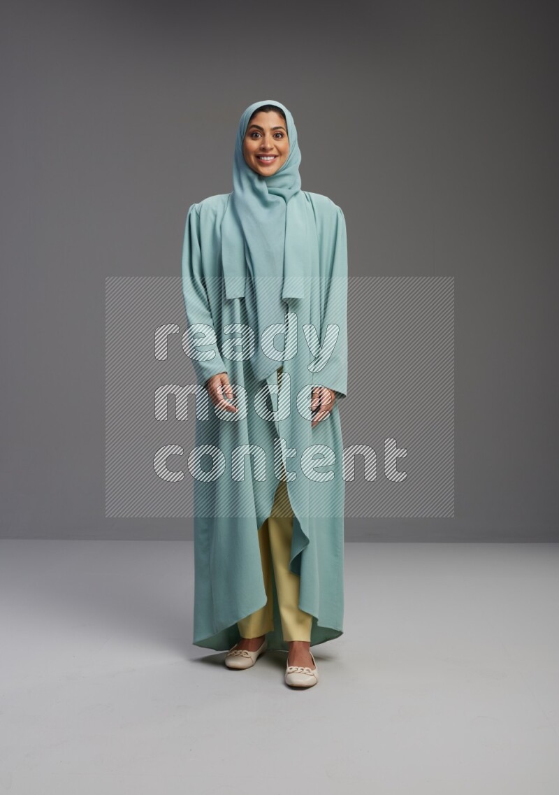 Saudi Woman wearing Abaya standing interacting with the camera on Gray background