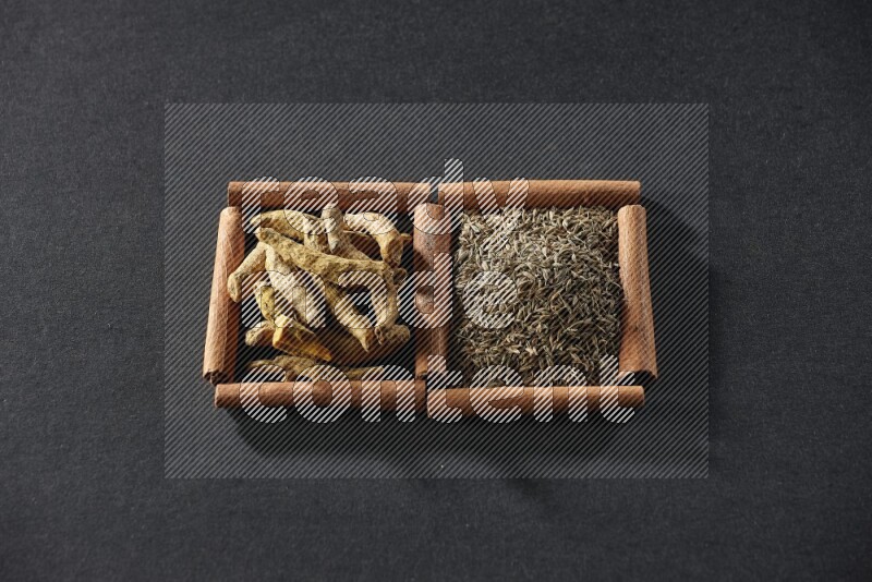 2 squares of cinnamon sticks full of cumin and turmeric fingers on black flooring