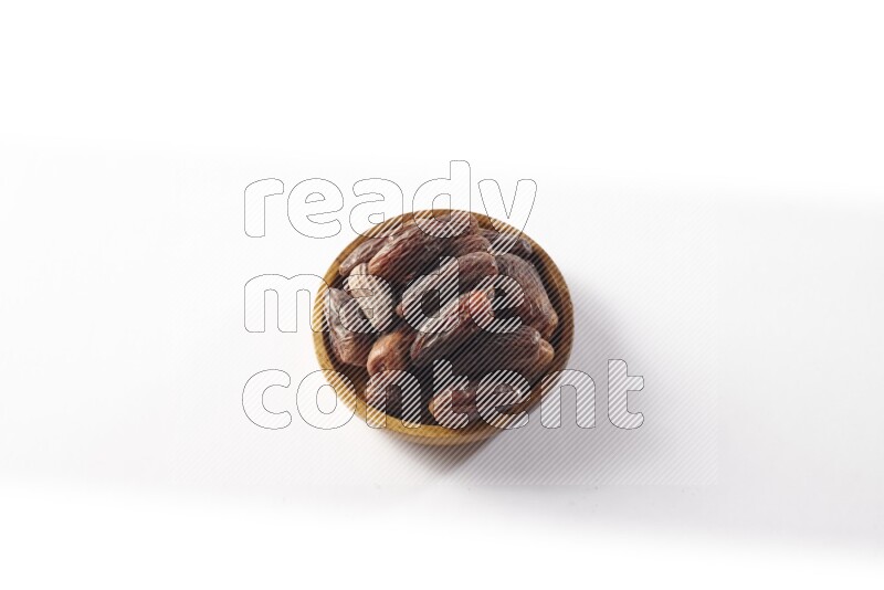 Dates in a wooden bowl on white background