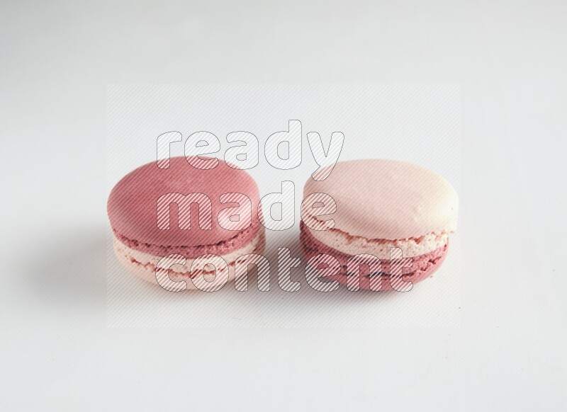 45º Shot of two Pink Litchi Raspberry macarons on white background